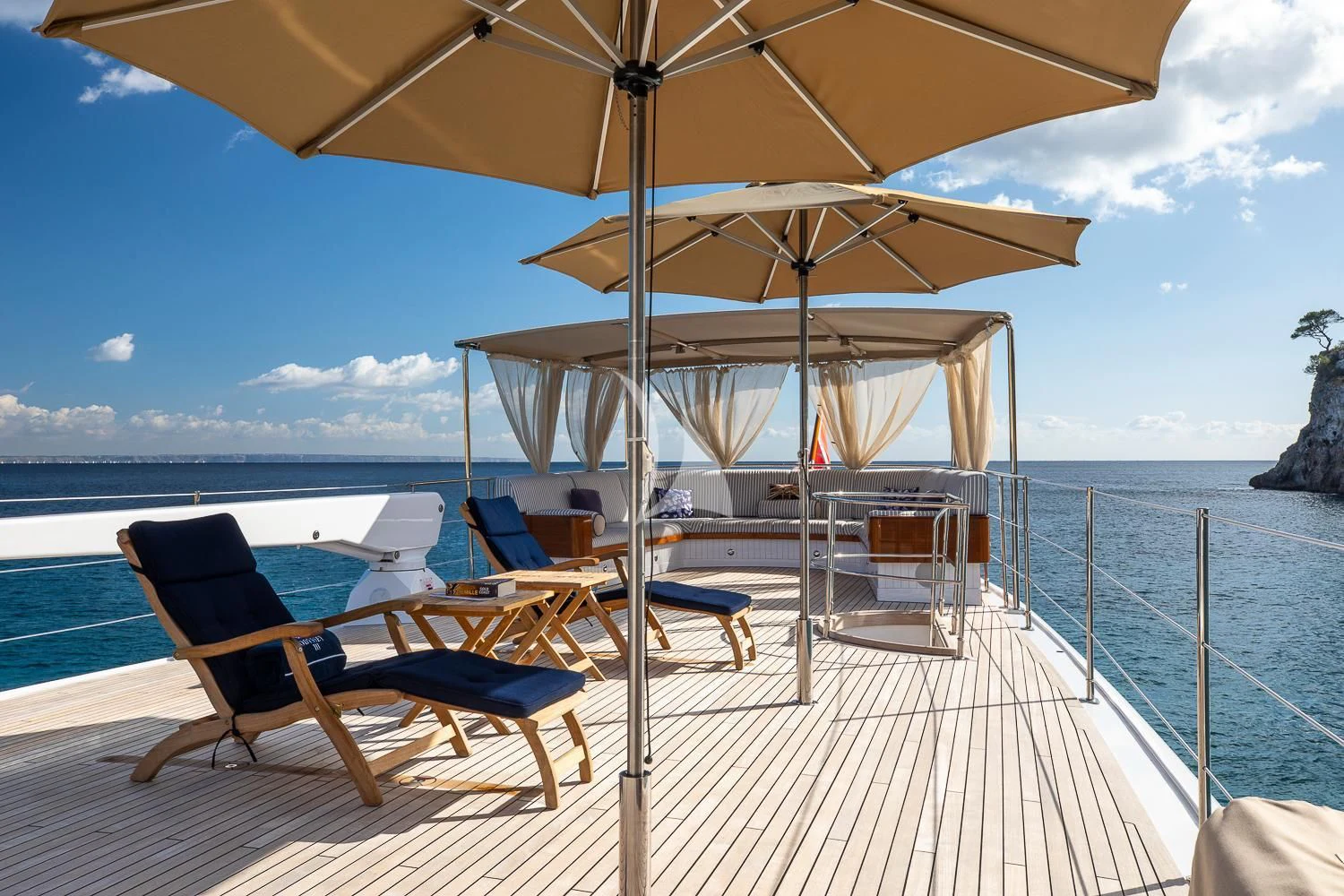 a lounge chair and umbrella on a deck overlooking the ocean aboard ODYSSEY III Yacht for Sale
