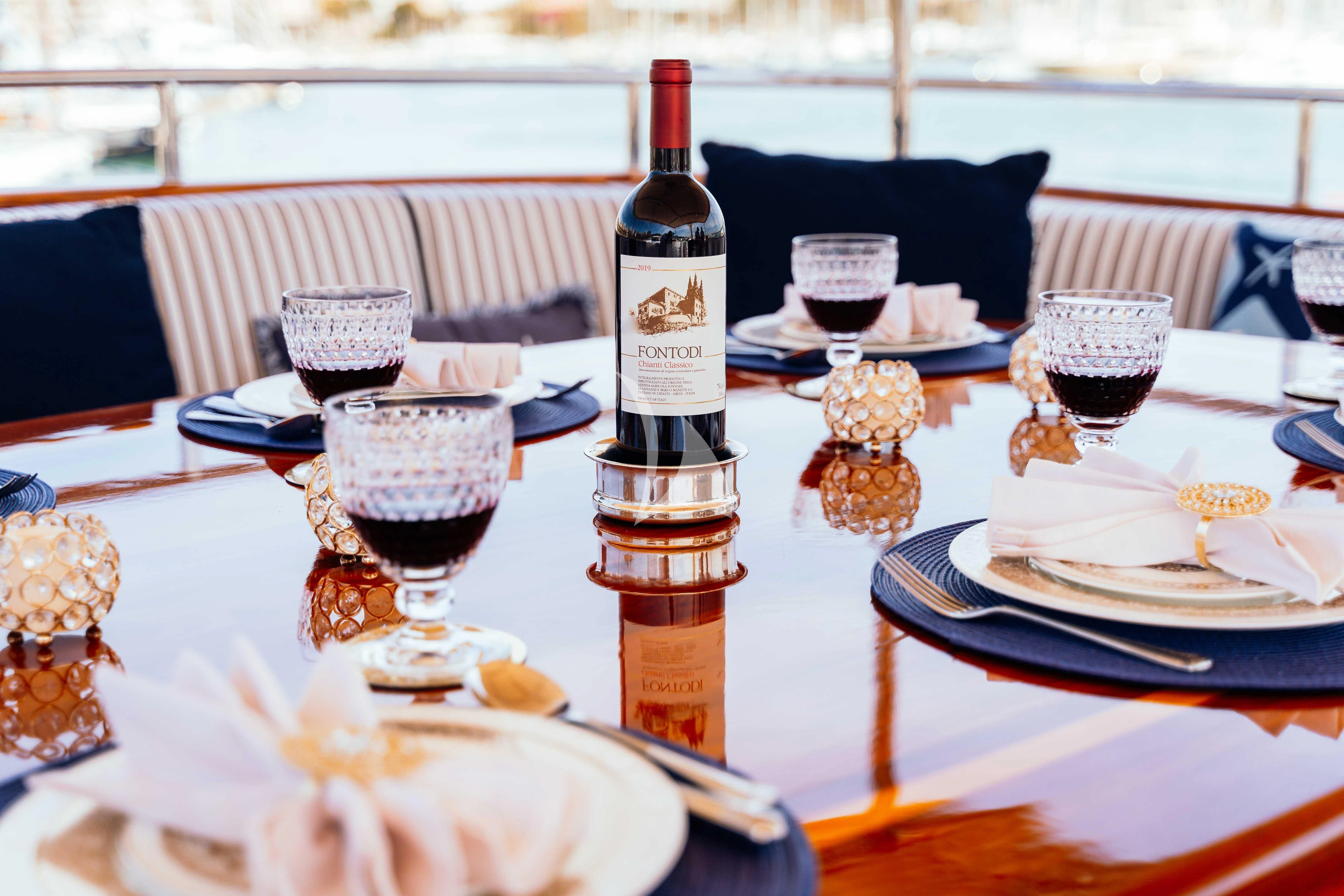 a table with plates and wine bottles aboard ODYSSEY III Yacht for Sale