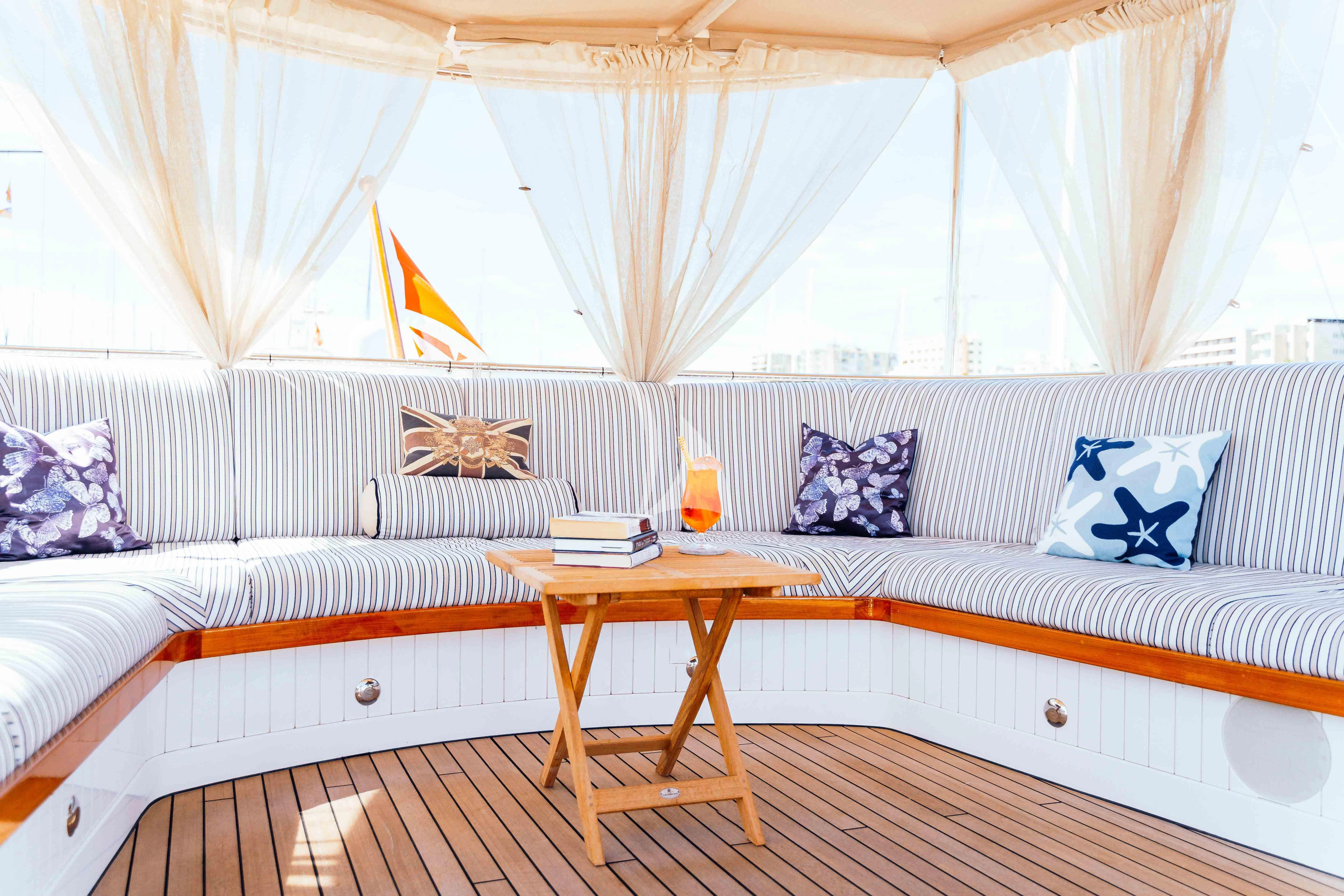 a bed with a white sheet and a table with a glass on it aboard ODYSSEY III Yacht for Sale