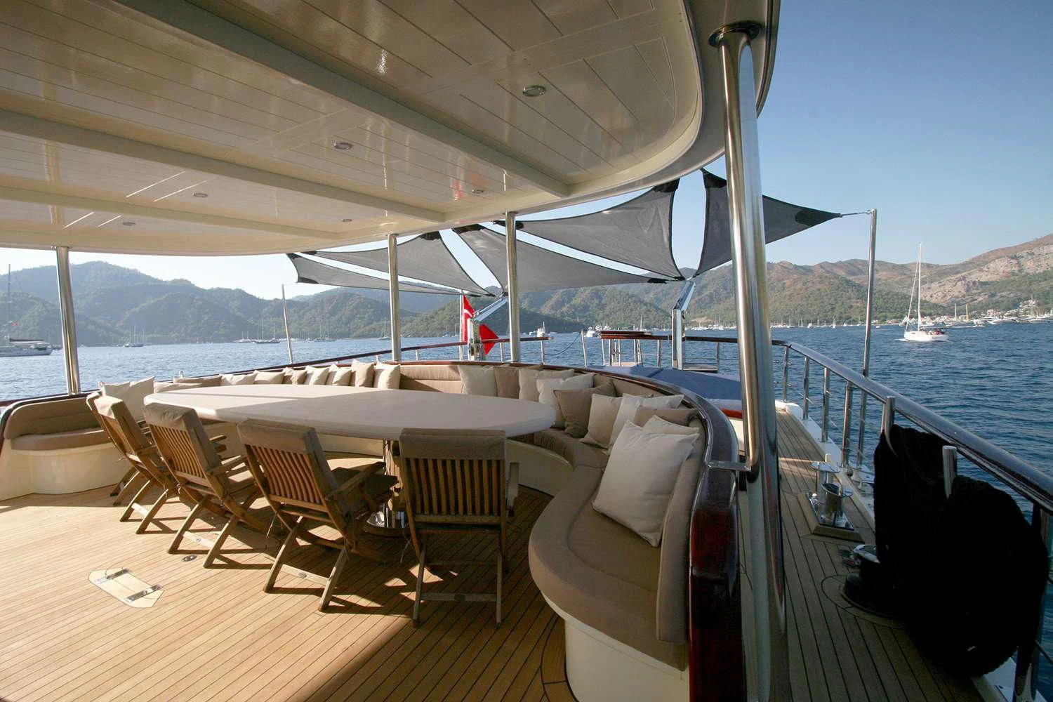a deck with a large body of water and a large boat in the background aboard ALWAYS SMILE Yacht for Charter