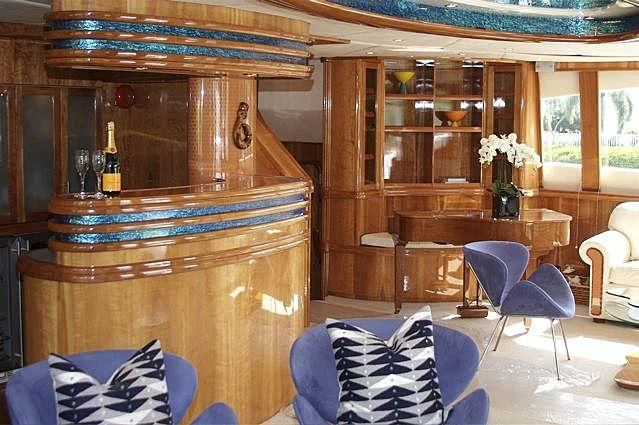 a room with a wood cabinet and chairs and a table with a vase of flowers on it aboard AZURE II Yacht for Sale