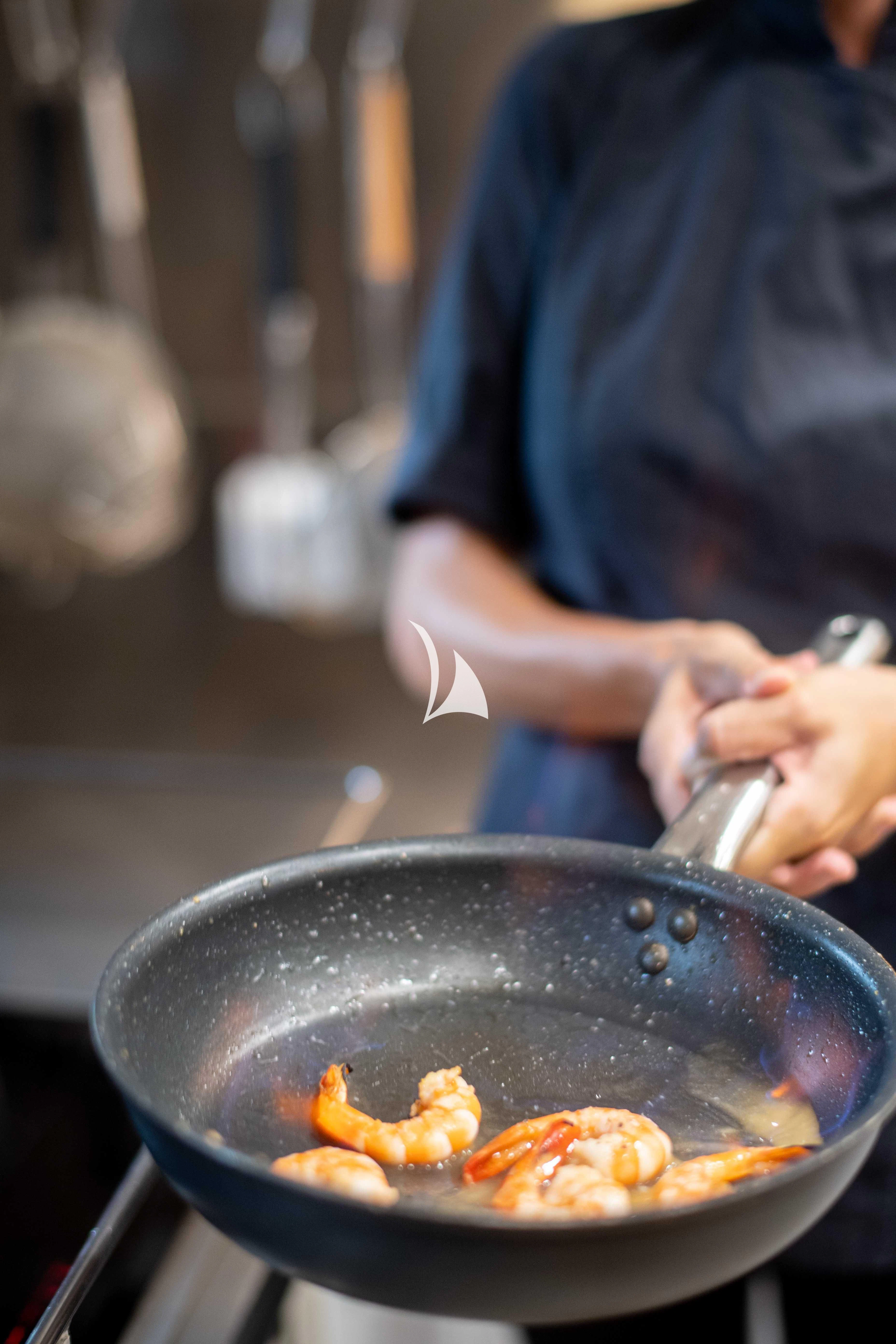a person cooking food in a pot aboard LATITUDE Yacht for Sale