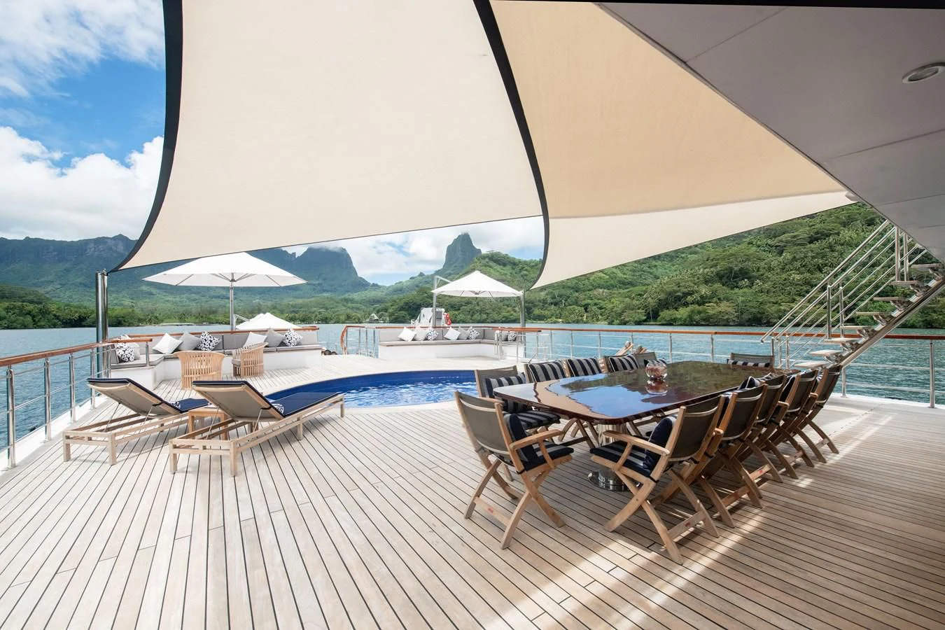 a deck with a pool and a view of mountains and water aboard LATITUDE Yacht for Sale