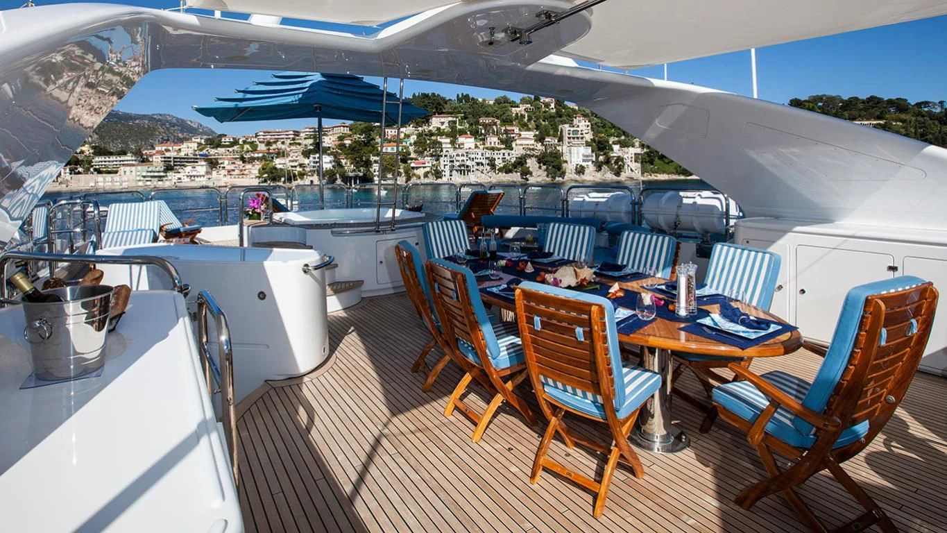 a deck with a table and chairs aboard DOMANI Yacht for Sale