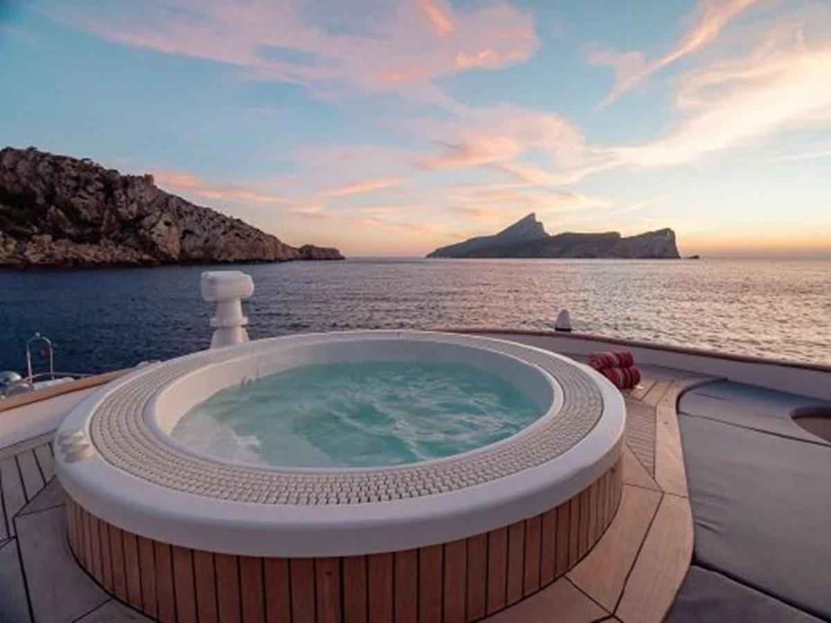 a round tub with a blue water and a rocky shore in the background aboard CHARISMA Yacht for Sale
