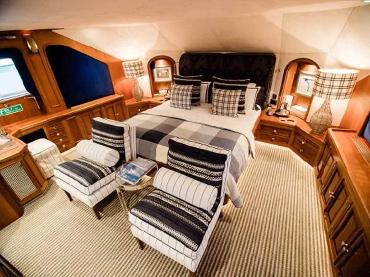 a bedroom with a bed and a chair aboard CHARISMA Yacht for Sale