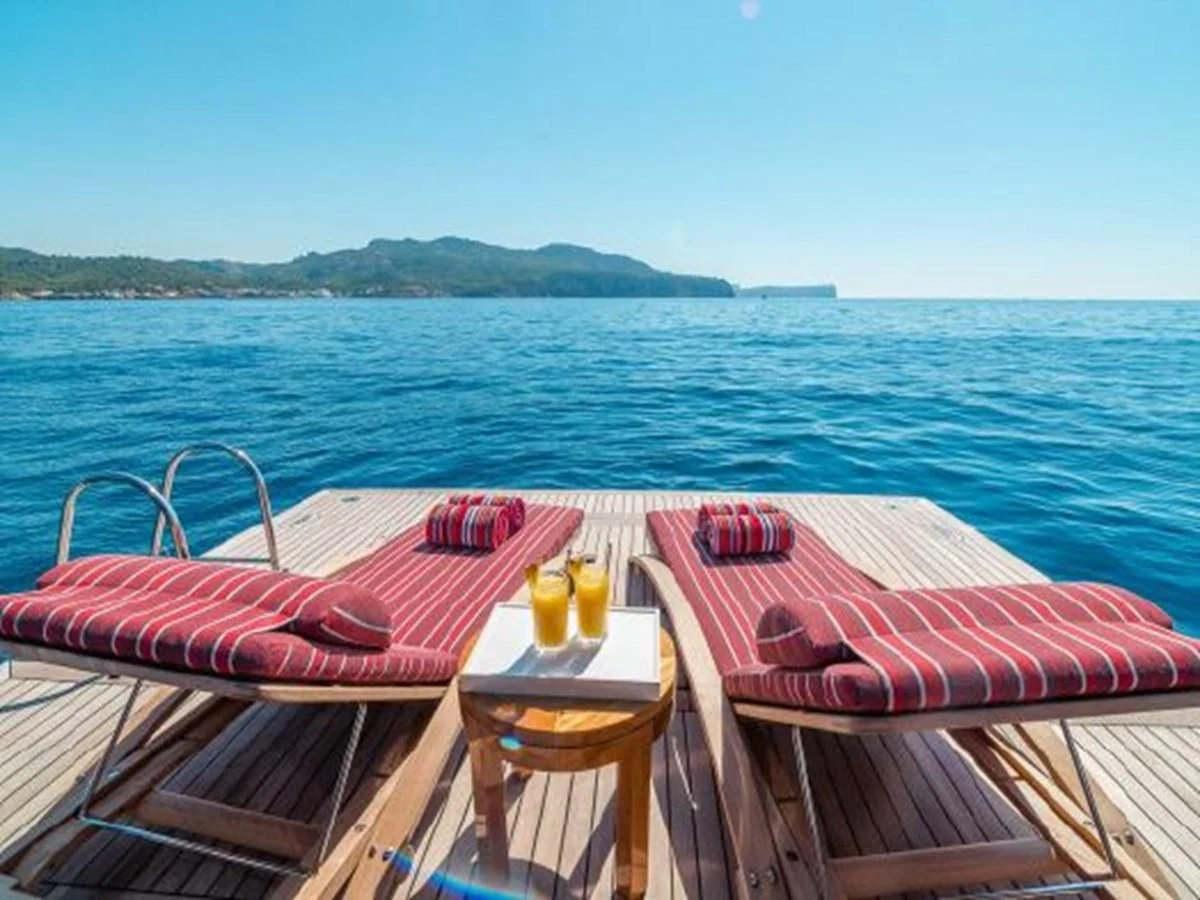 a deck with a table and chairs on it by the water aboard CHARISMA Yacht for Sale