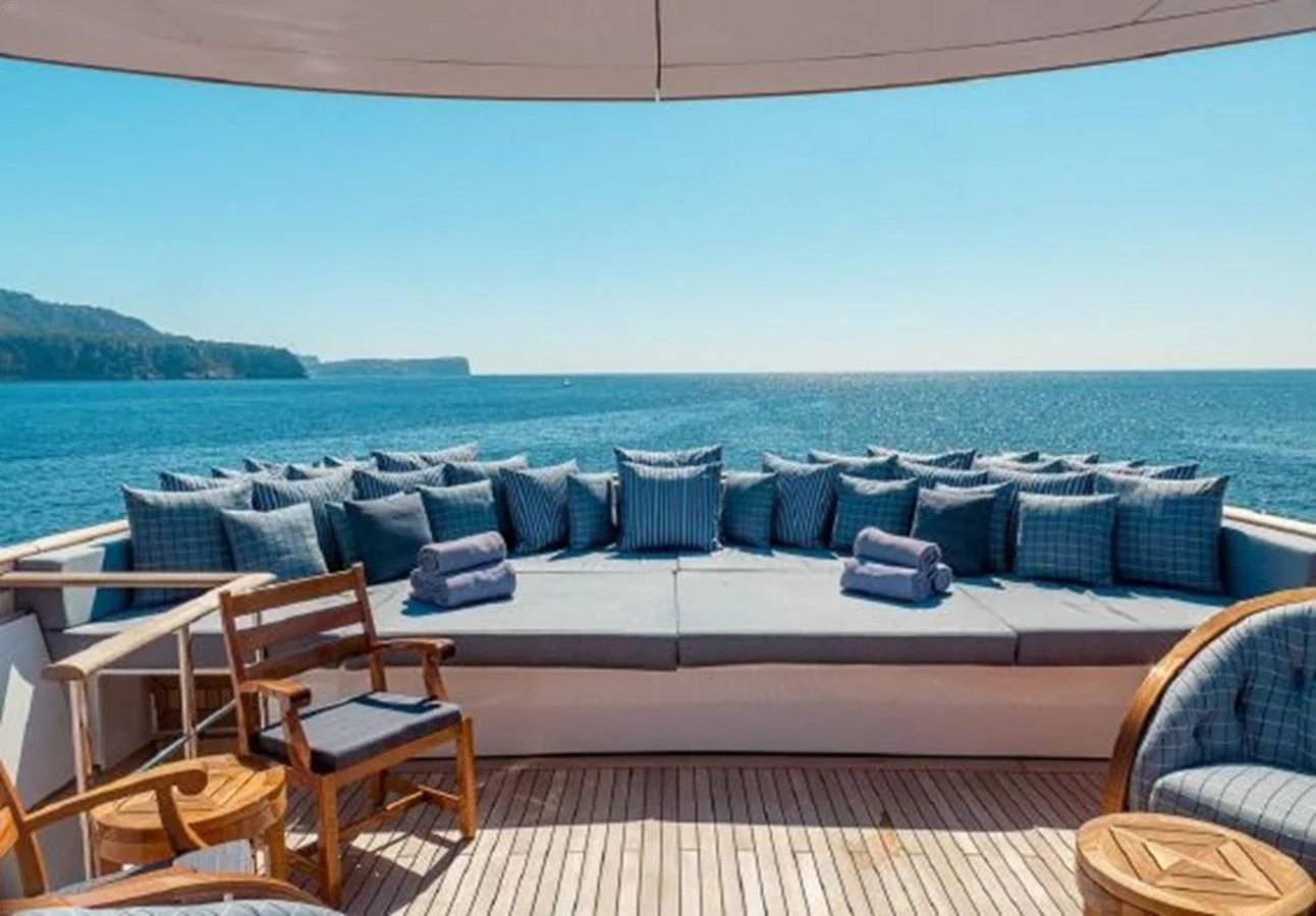 a couch and chairs on a deck overlooking a body of water aboard CHARISMA Yacht for Sale