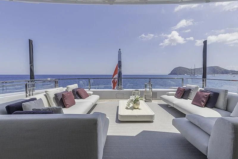 a large white lounge chair with a white table and white couches on a beach with a flag aboard LEL Yacht for Sale