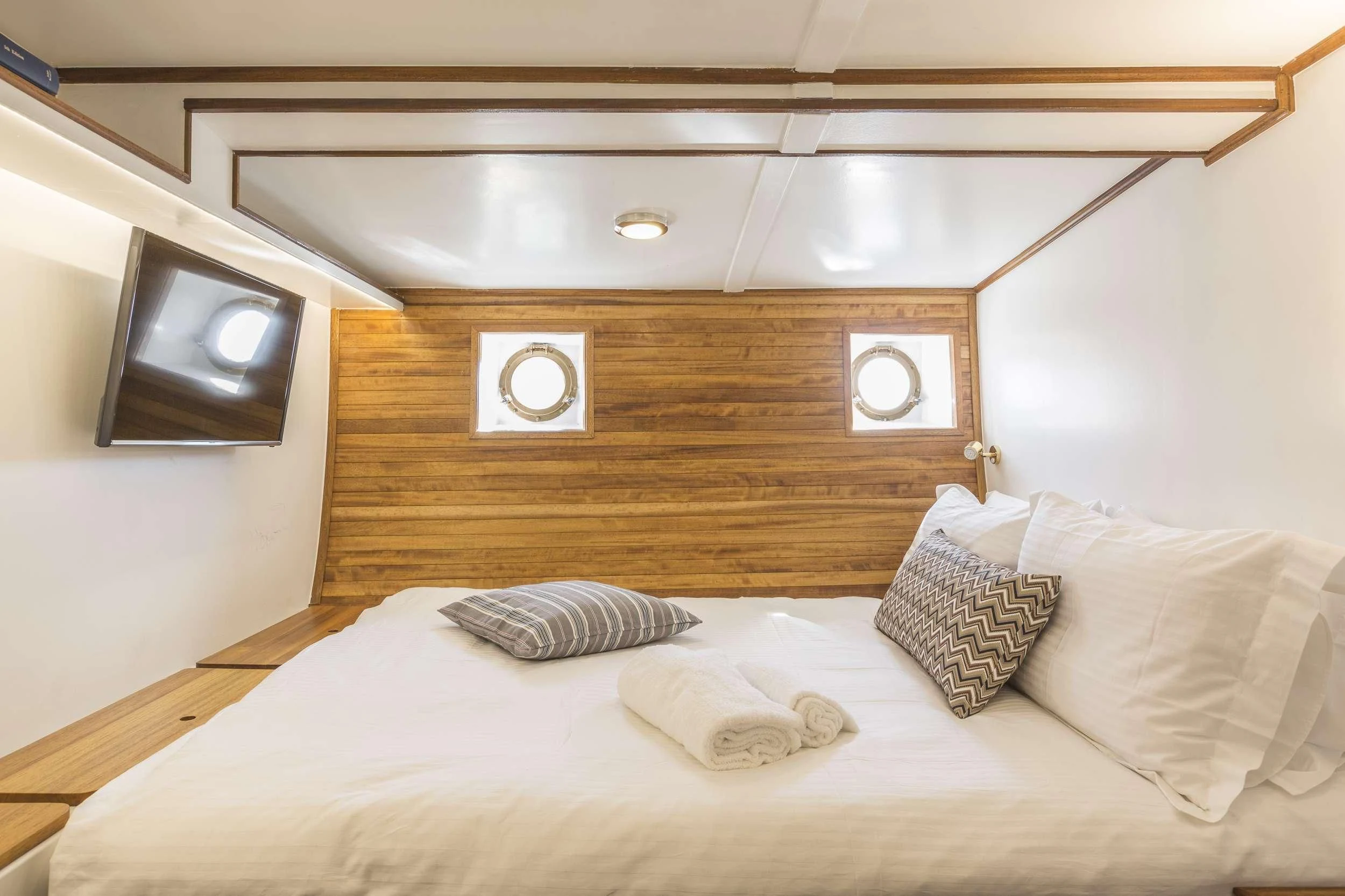 a bed with pillows and a television aboard COSMOS Yacht for Sale
