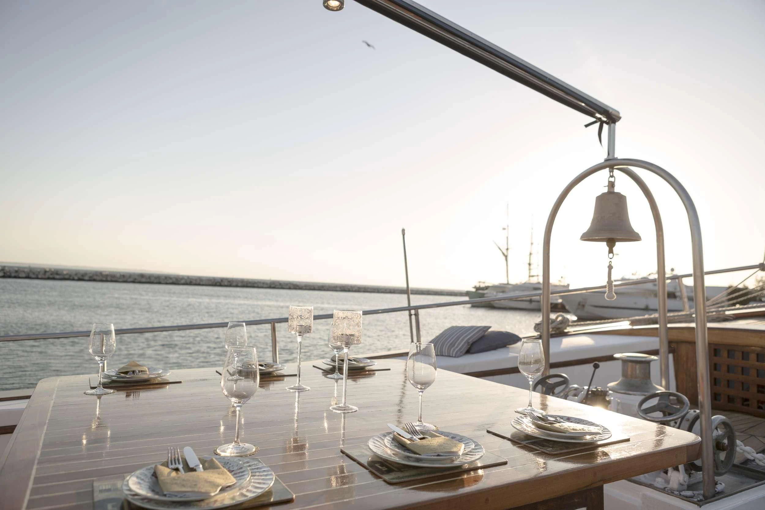 a table with wine glasses and a view of the ocean aboard COSMOS Yacht for Sale