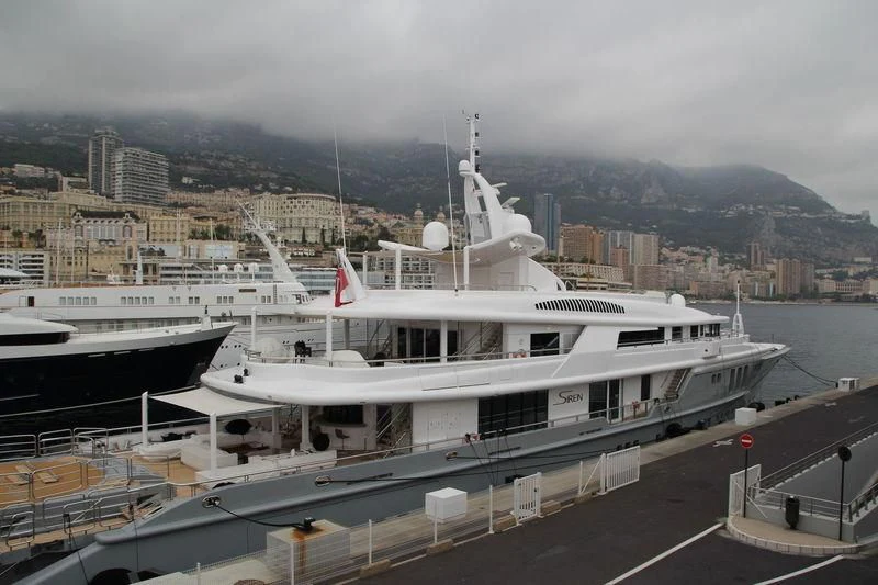 a large white boat in a harbor aboard SIREN Yacht for Sale