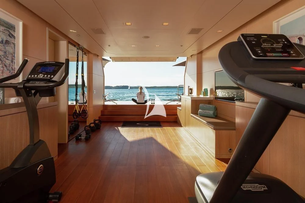 a person sitting on a bench in a room with a large window aboard SIREN Yacht for Sale