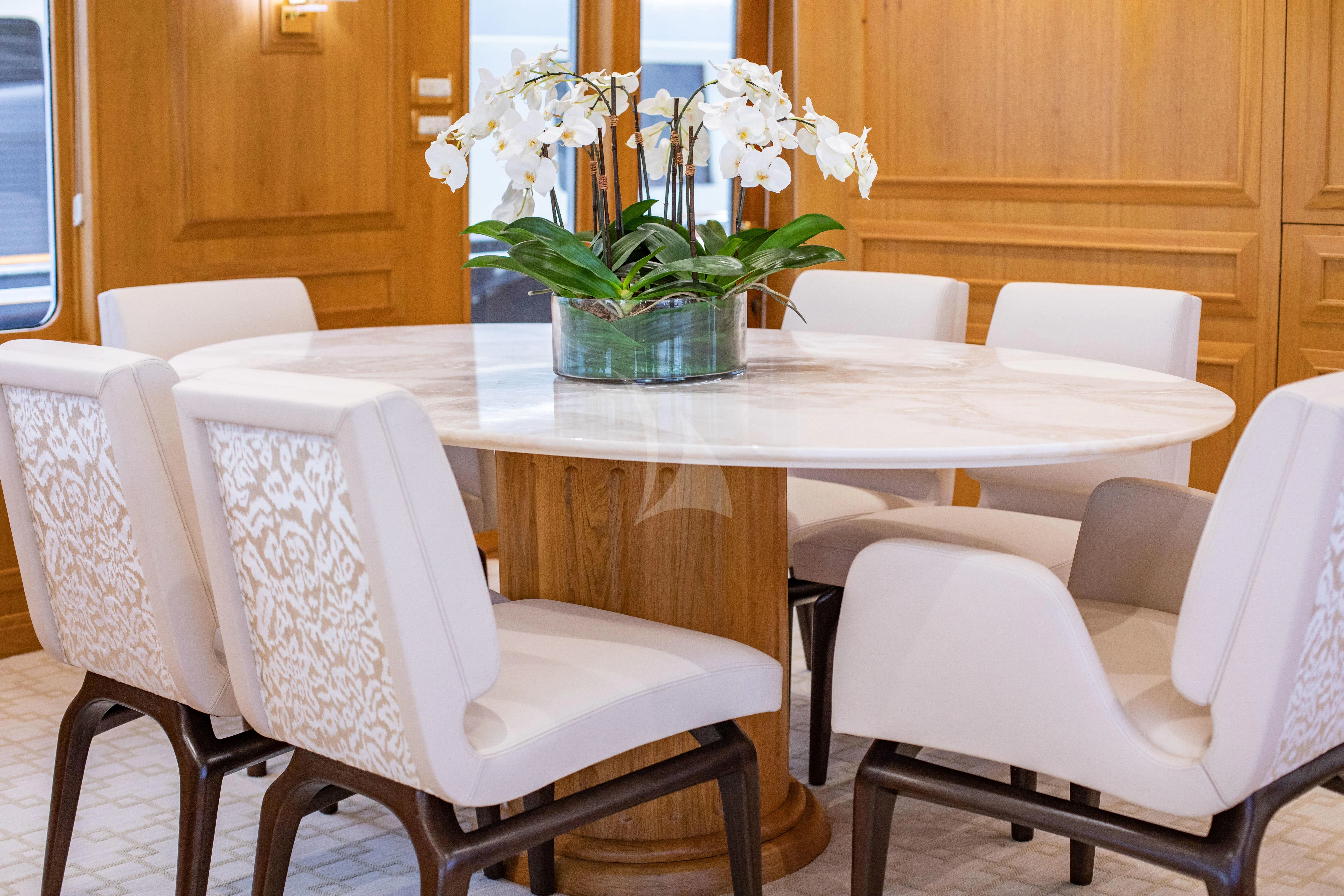 a table with chairs and a vase of flowers on it aboard VIAGGIO Yacht for Sale