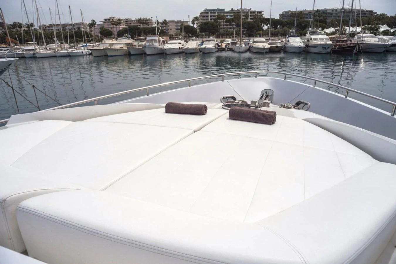 a white boat in a harbor with Ice hockey rink in the background aboard A&O Yacht for Sale