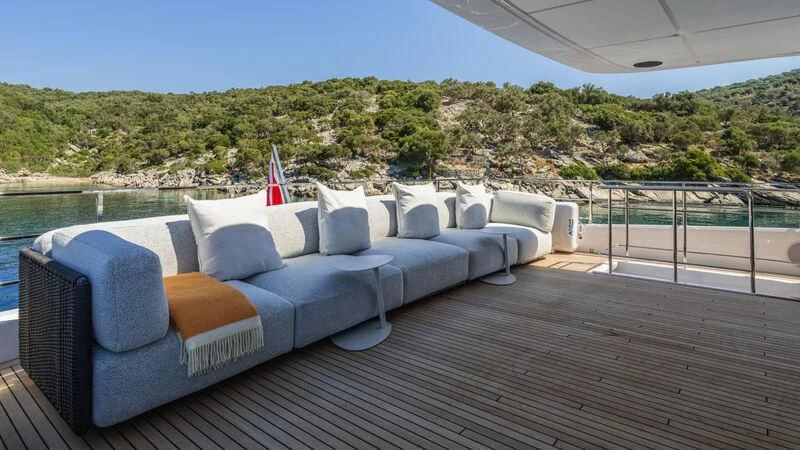 a large blue couch on a deck overlooking a body of water aboard AT ONE Yacht for Charter