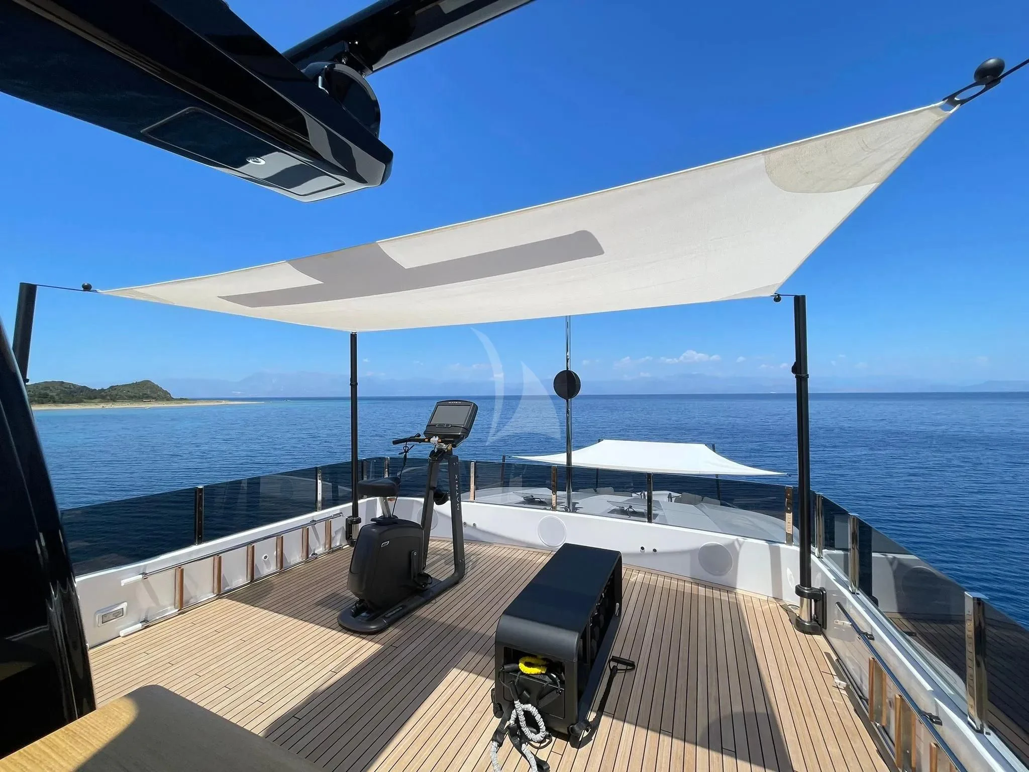 a deck with a view of the ocean and a large boat aboard AT ONE Yacht for Charter