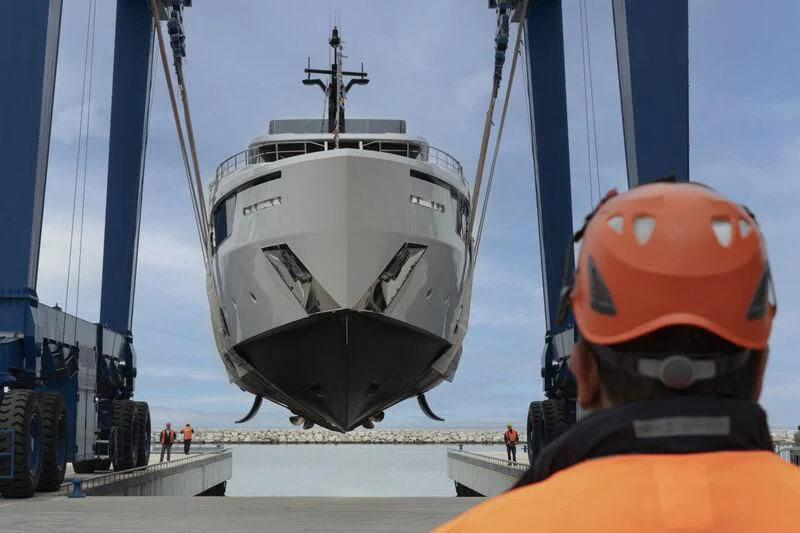 a person wearing a helmet and orange vest next to a large ship aboard AT ONE Yacht for Charter