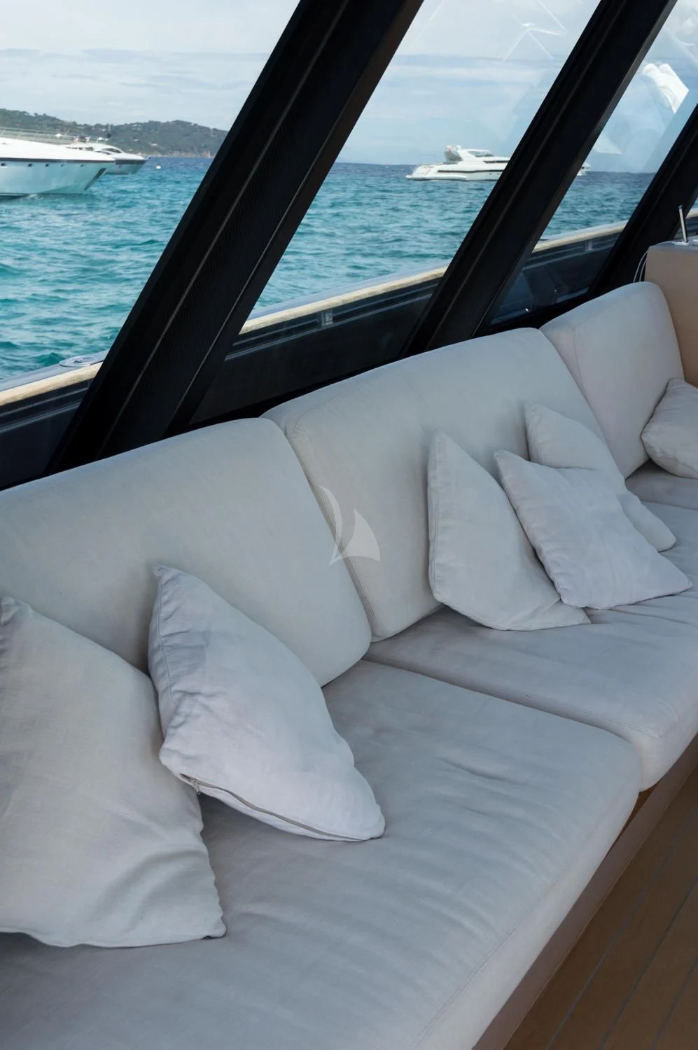a white couch with pillows in a car with a body of water in the background aboard ASH Yacht for Sale