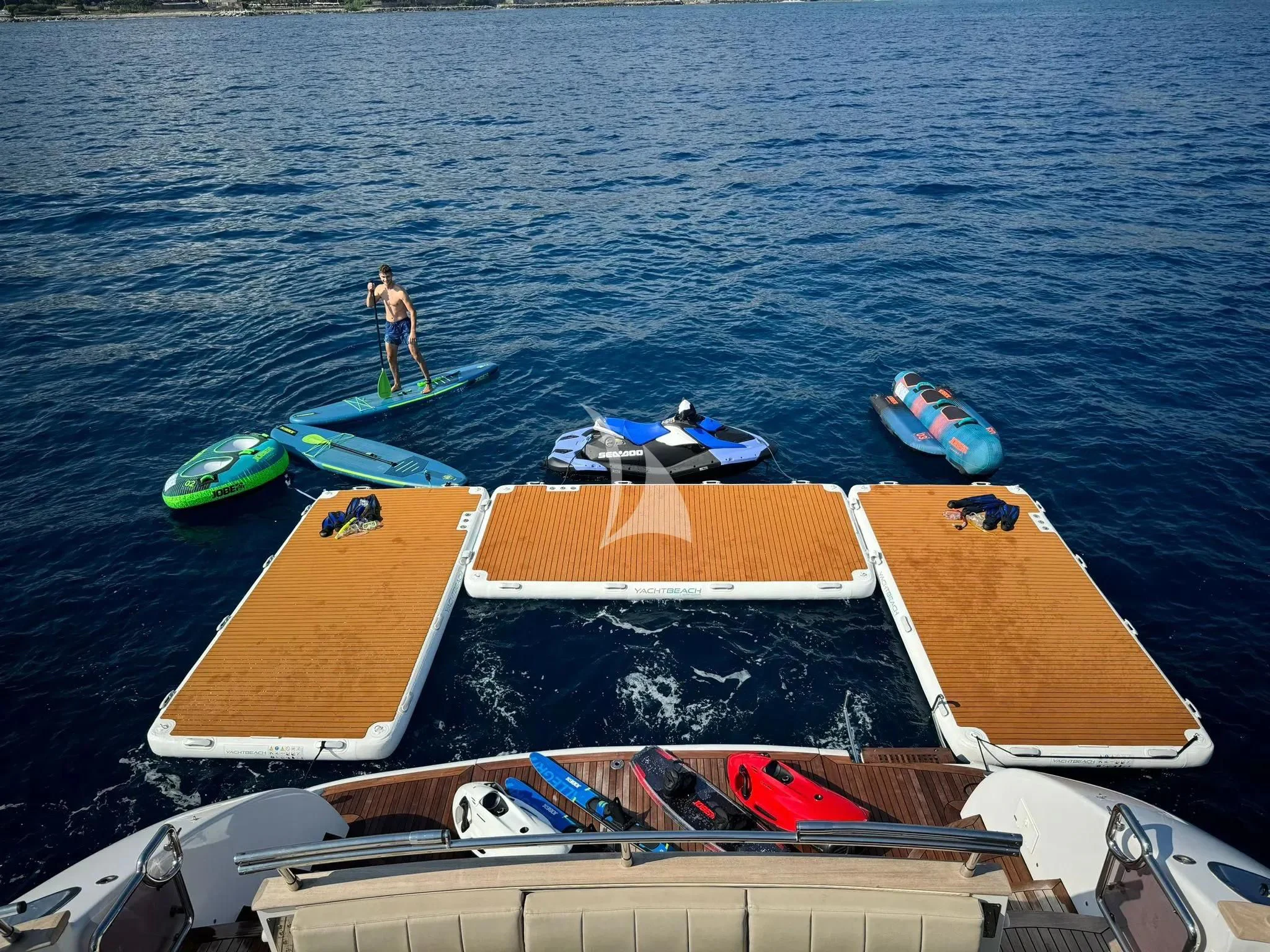 a person on a surfboard next to a row of boats aboard DADDY'S DREAM 888 Yacht for Charter
