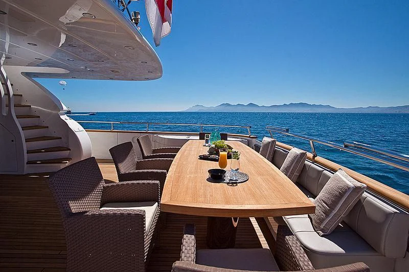 a table and chairs on a deck overlooking the ocean aboard DADDY'S DREAM 888 Yacht for Charter