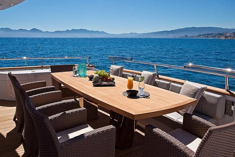 a table with chairs and a view of the ocean aboard DADDY'S DREAM 888 Yacht for Charter