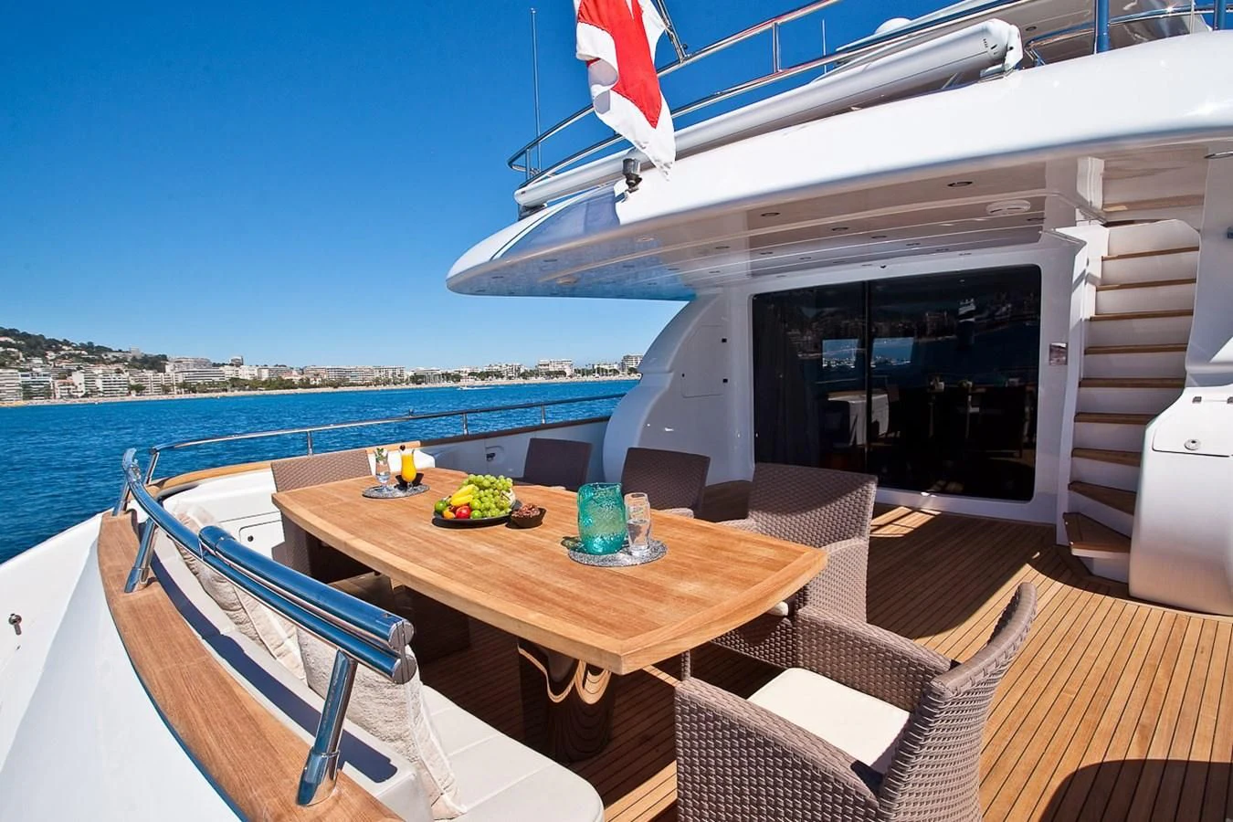 a table on a deck with chairs and a flag on the side aboard DADDY'S DREAM 888 Yacht for Charter