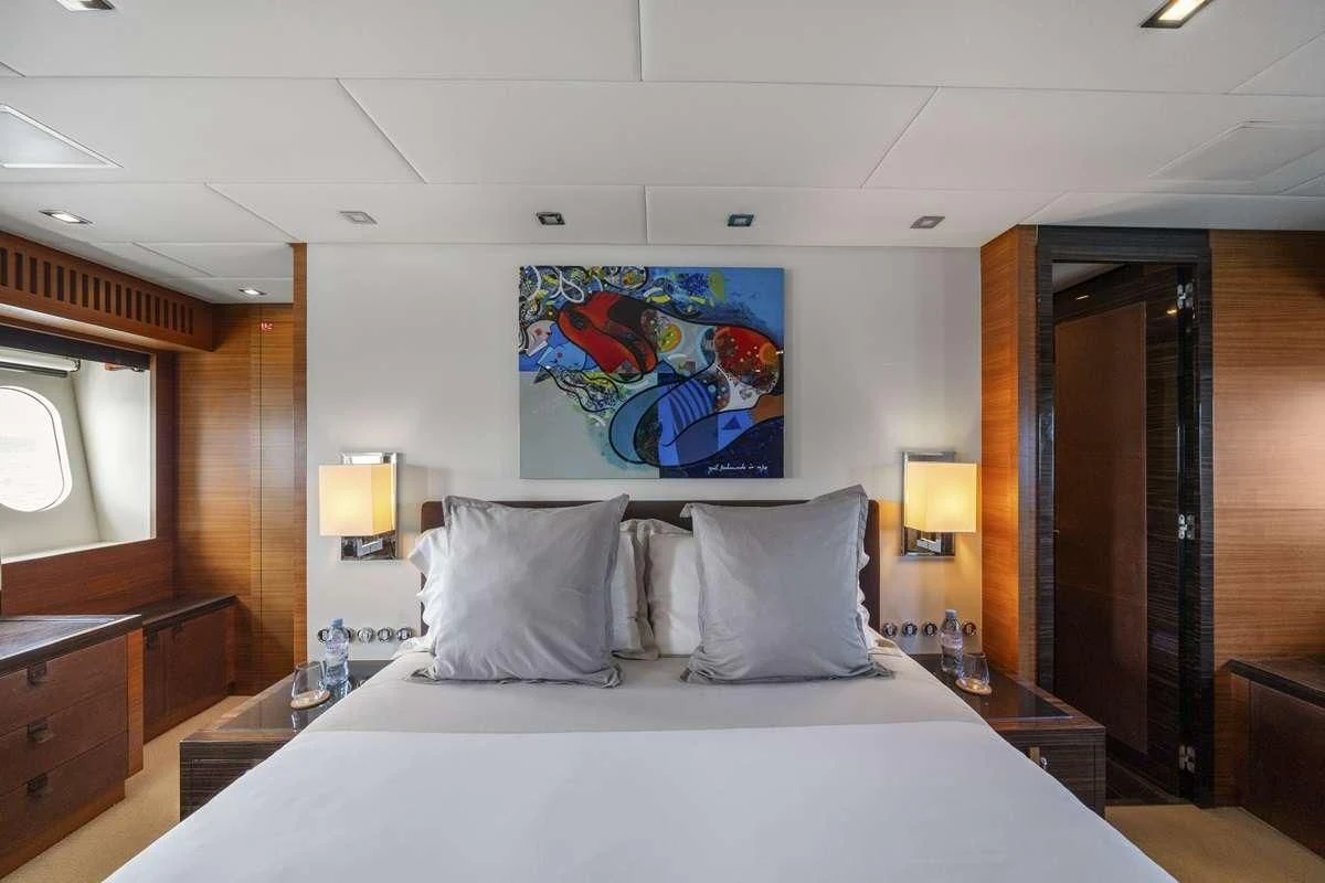 a bed with a white sheet and pillows in a room with wood cabinets aboard ECLAT Yacht for Sale