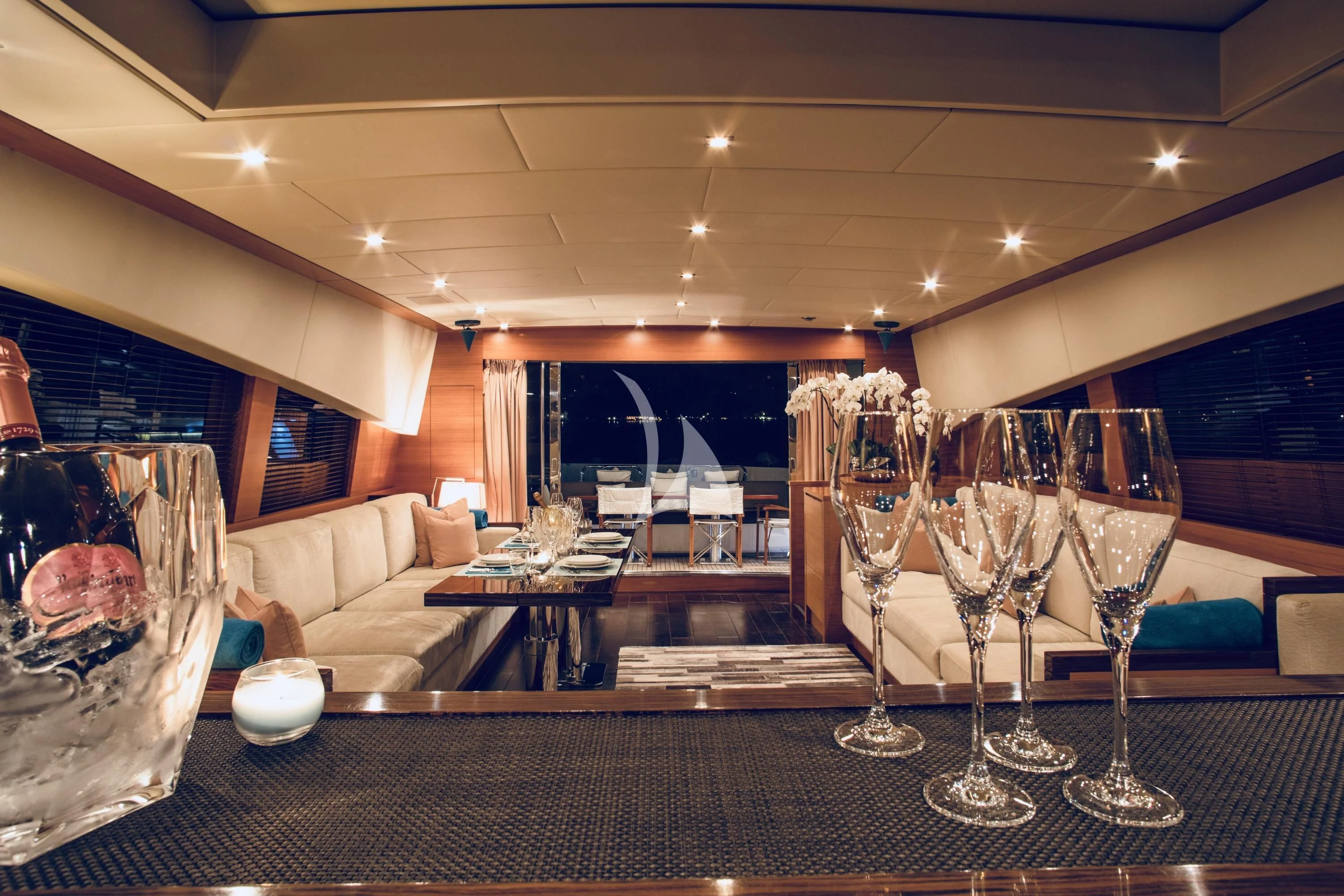 a group of wine glasses on a table in a room with a couch and a television aboard ECLAT Yacht for Sale