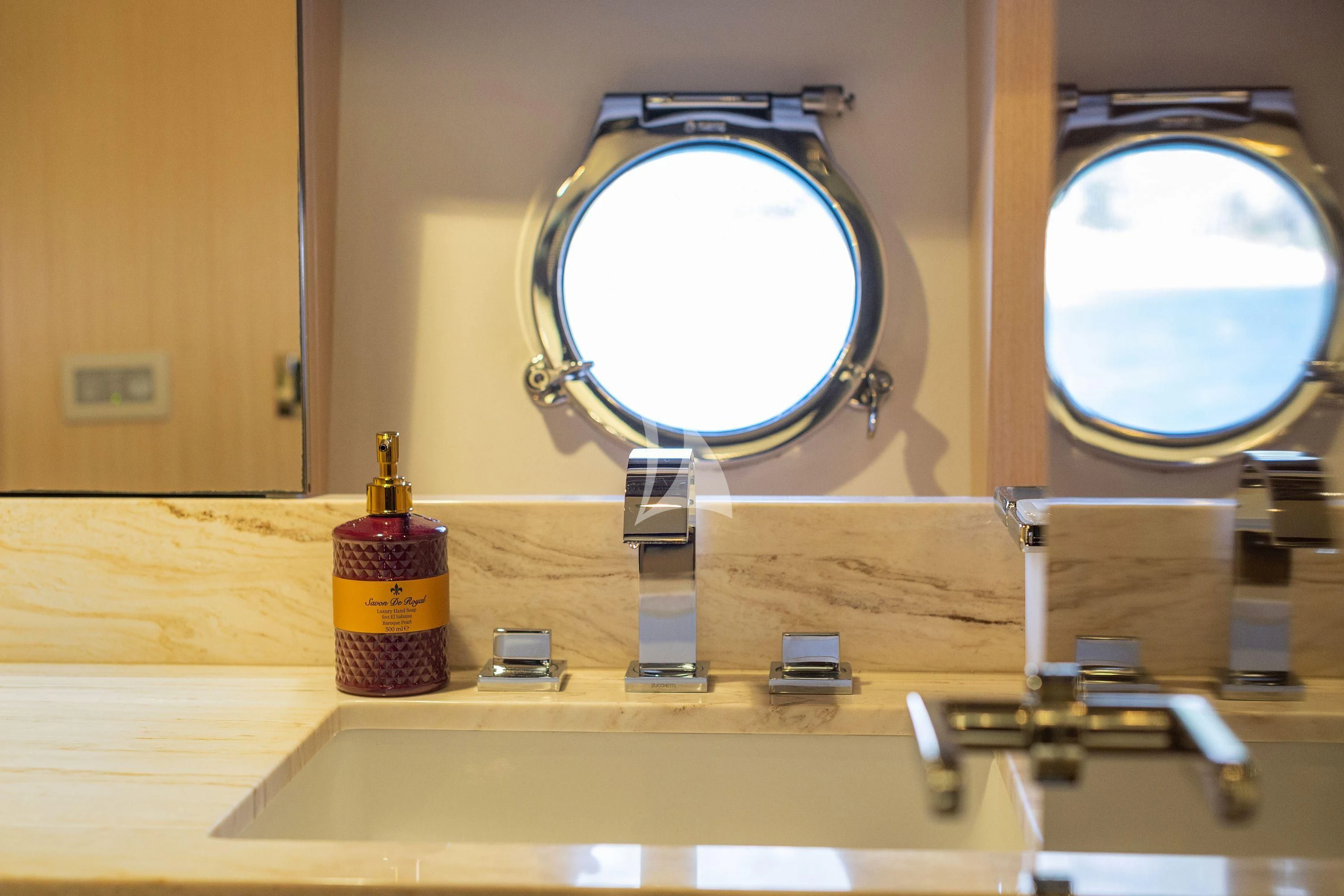 a bathroom sink with a round mirror aboard HUBO Yacht for Sale