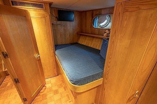 a bedroom with a bed and a dresser aboard IVORY LADY Yacht for Sale