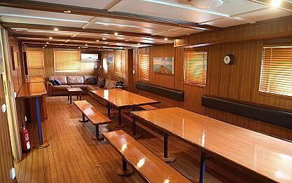 a room with tables and benches aboard MAYA'S DUGONG Yacht for Sale