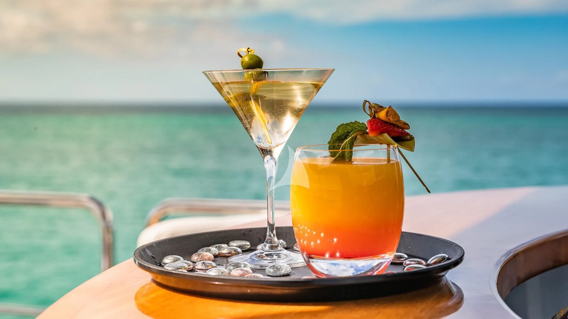 a glass of champagne with a slice of fruit on a plate with a glass of orange juice on aboard TAIL LIGHTS Yacht for Sale