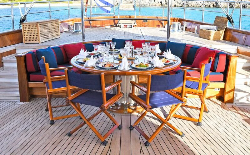 a table set with chairs and a table with food on it aboard TAMARITA Yacht for Sale