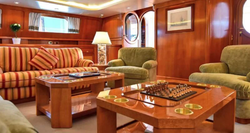 a living room with a table and couches aboard TAMARITA Yacht for Sale