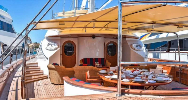 a deck with a table and chairs on it aboard TAMARITA Yacht for Sale