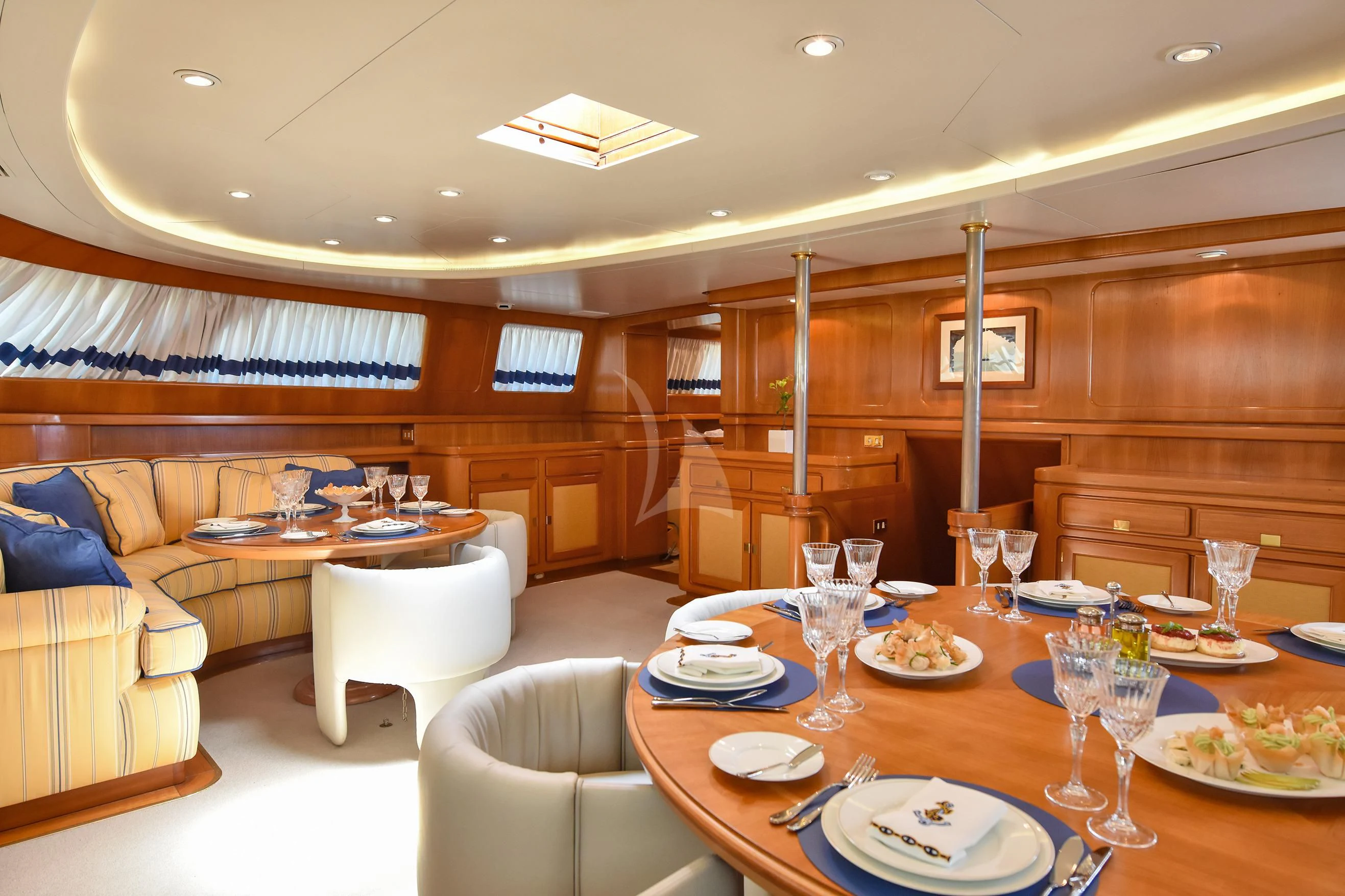 a large living room with a dining table and chairs aboard TAMARITA Yacht for Sale