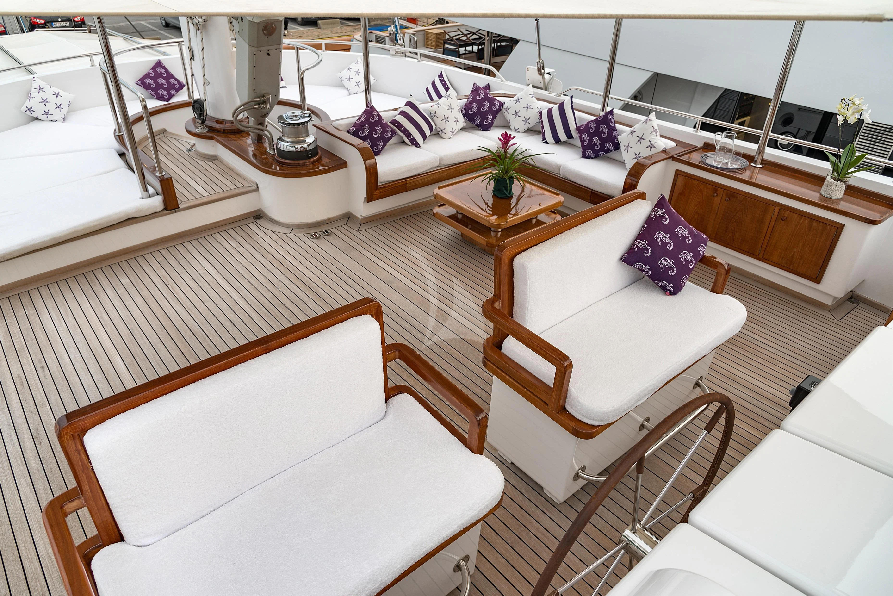 a room with a couch and a table with a chair aboard TAMARITA Yacht for Sale