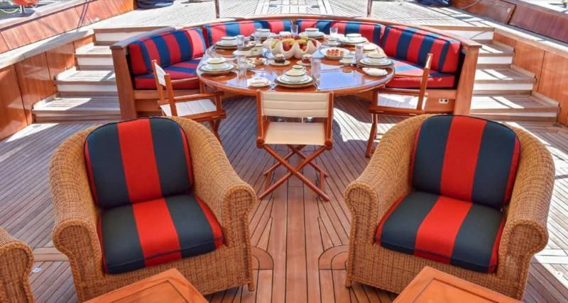 a table with chairs and a couch aboard TAMARITA Yacht for Sale
