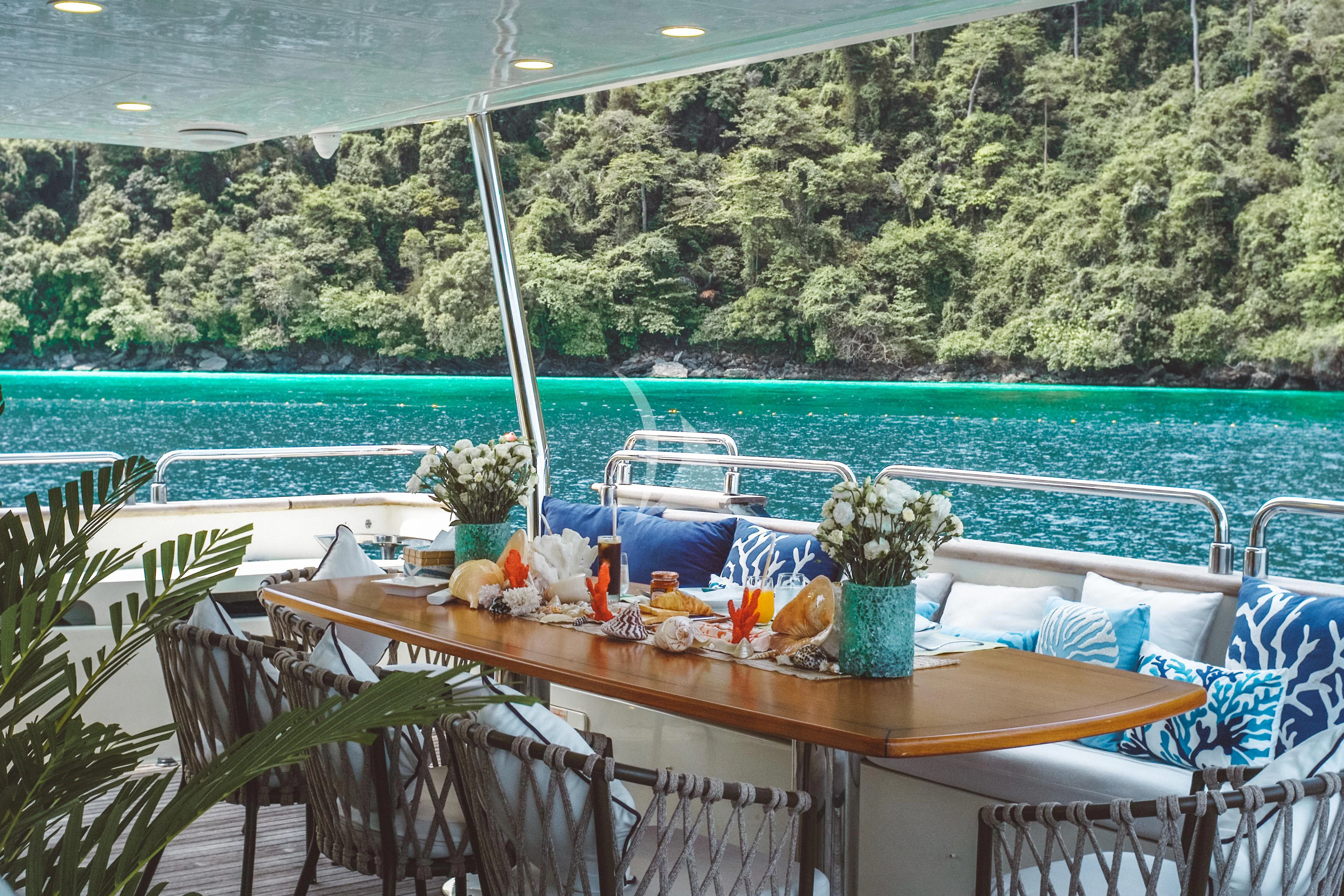 a table with chairs and plants on it by a body of water aboard FOR YOUR EYES ONLY Yacht for Charter