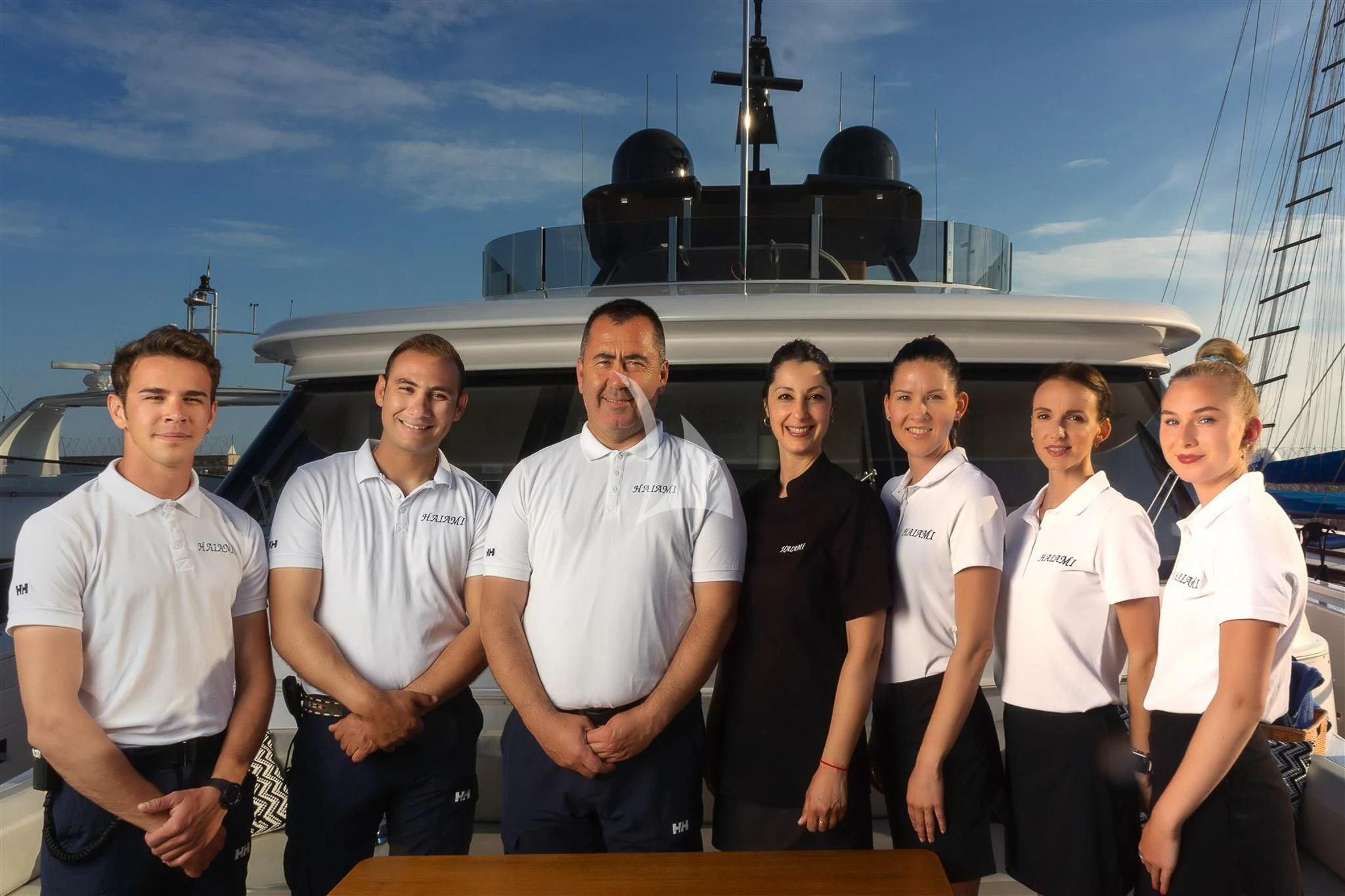 a group of people posing for a photo in front of a military ship aboard HAIAMI I Yacht for Charter