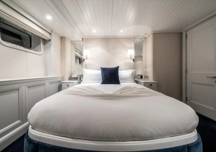 a large white bed with blue pillows aboard MOATIZE Yacht for Sale