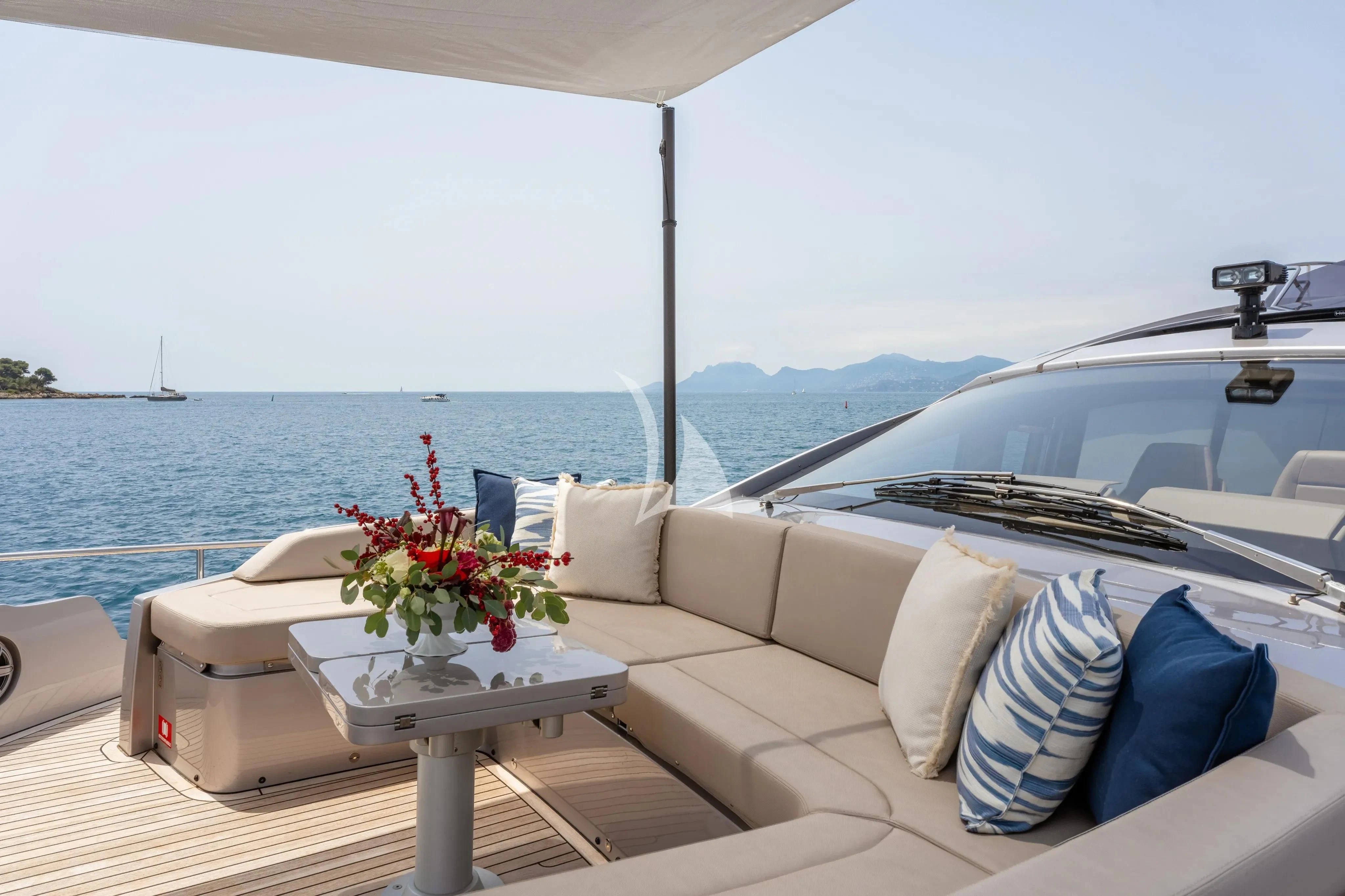a white couch with pillows and a table with flowers on it aboard CHERRY Yacht for Charter