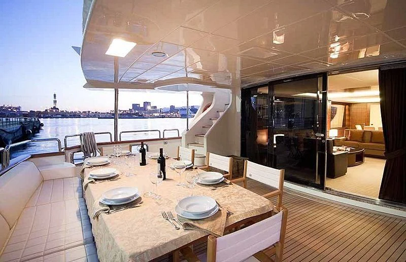 a table with plates and chairs on it next to a large body of water aboard TARTARUGA ONE 4J'S Yacht for Sale
