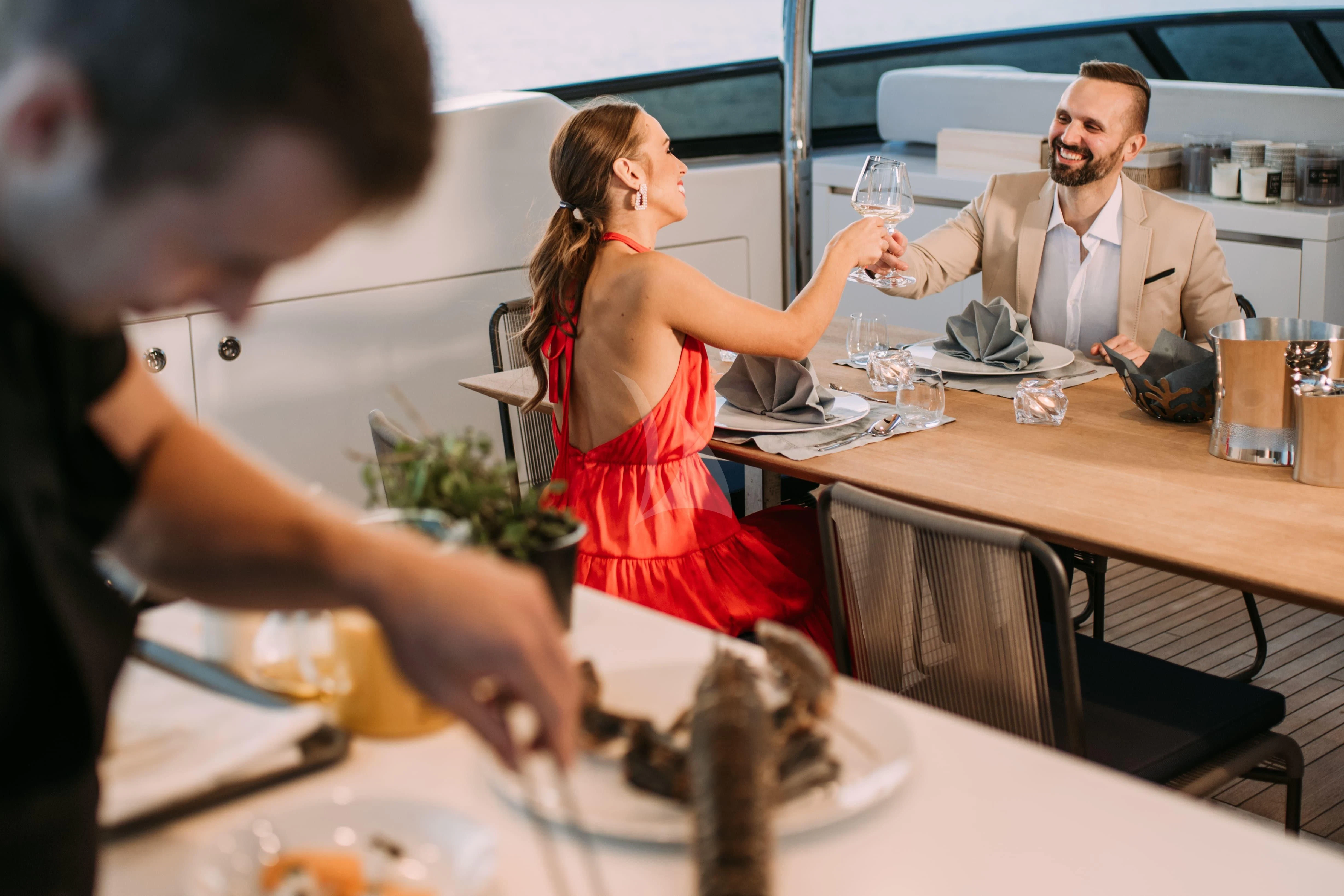 a man and woman at a restaurant table with a glass of wine aboard PARALOS Yacht for Charter