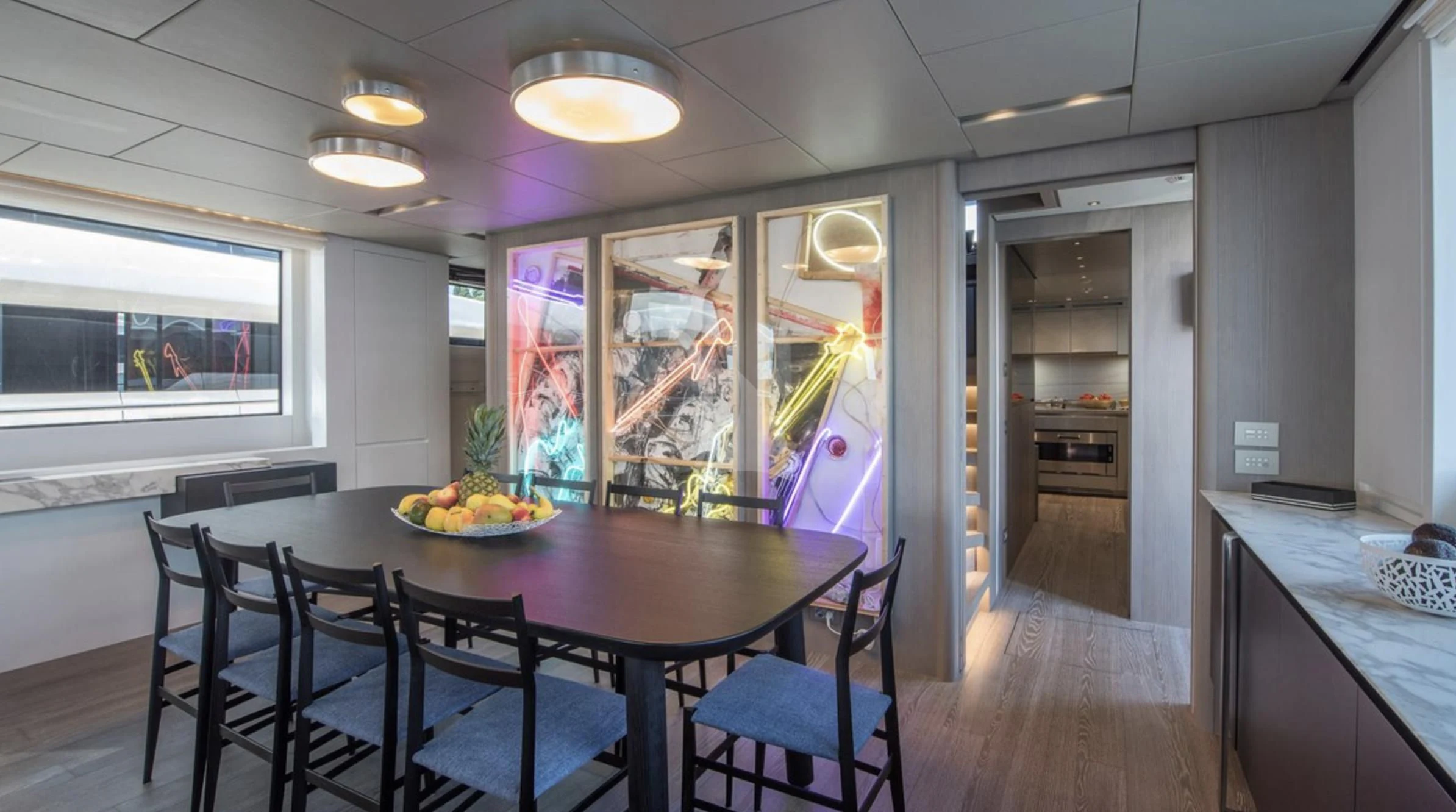 a dining table and chairs in a room with a large window aboard PARALOS Yacht for Charter