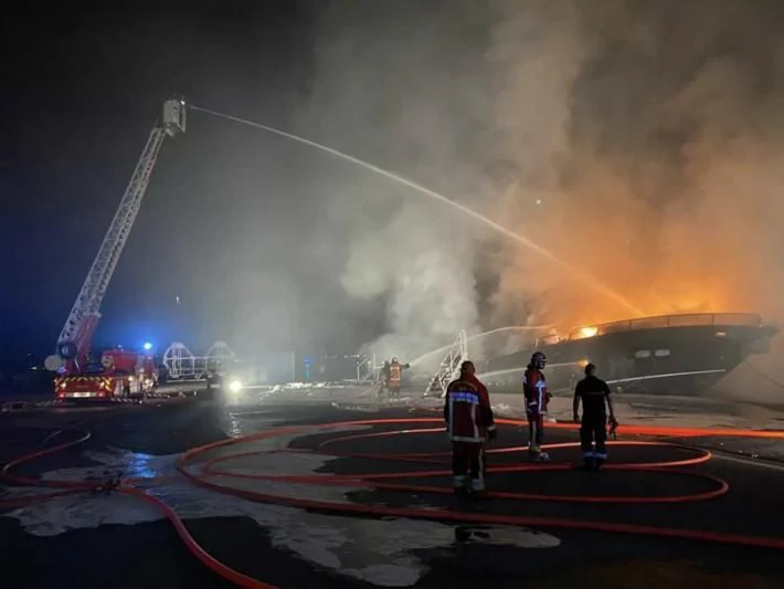 a group of people on a race track with a large fire in the background aboard BLACK DIAMOND Yacht for Sale