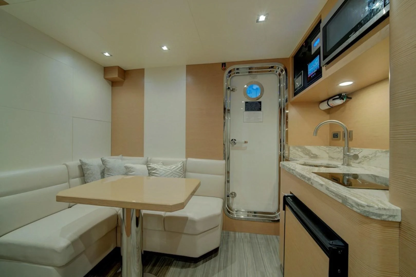 a room with a table and a couch and a sink aboard SEASUITE Yacht for Charter