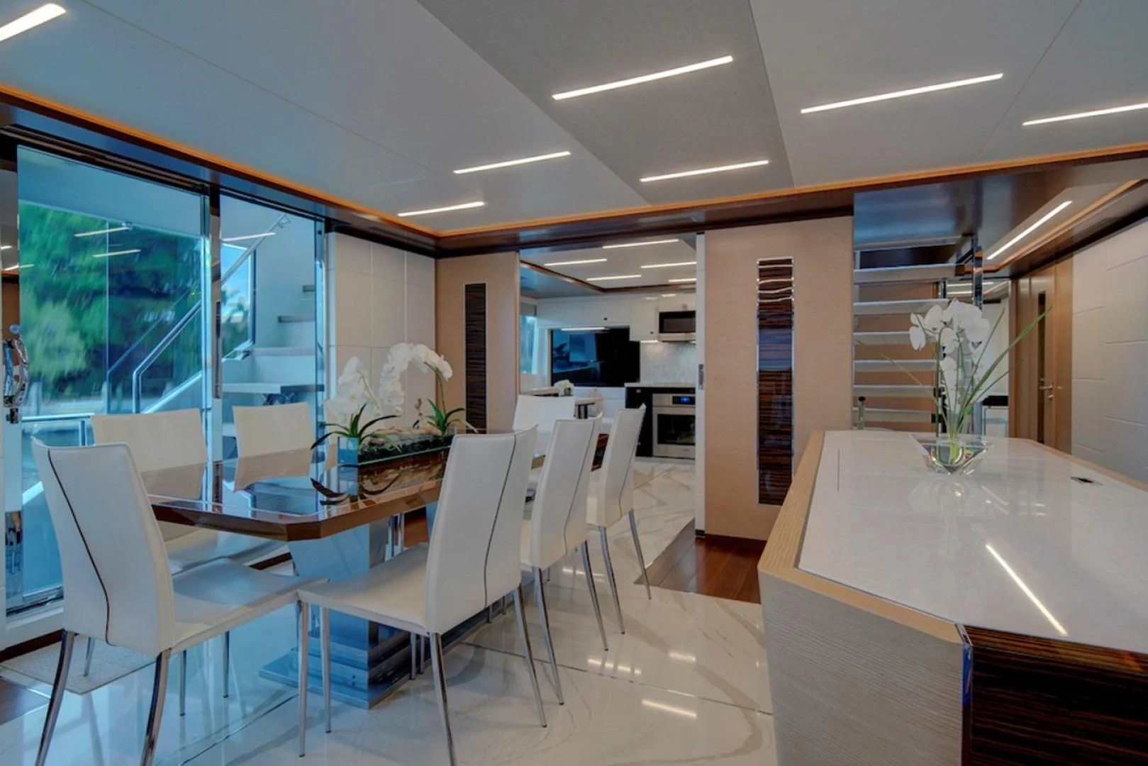 a room with white chairs and a table with a vase on it aboard SEASUITE Yacht for Charter