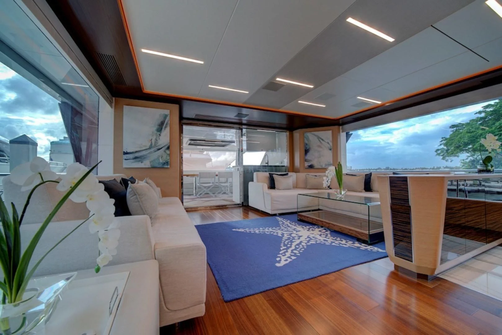a living room with a large blue rug and a large window aboard SEASUITE Yacht for Charter
